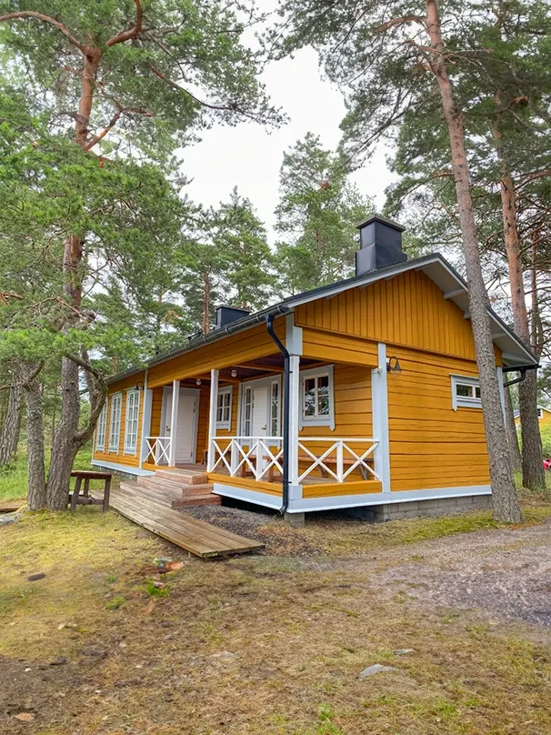 A cozy yellow wooden cabin nestled among trees.
