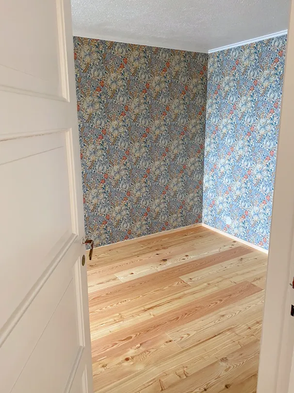 Room with floral wallpaper and wooden flooring