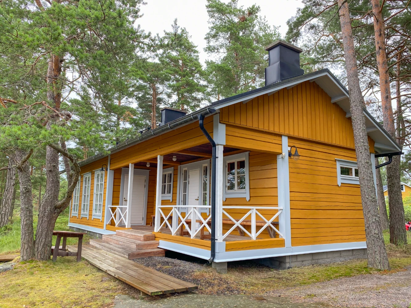 This image showcases a charming yellow wooden cabin with a porch, surrounded by lush trees, offering a serene and inviting atmosphere.