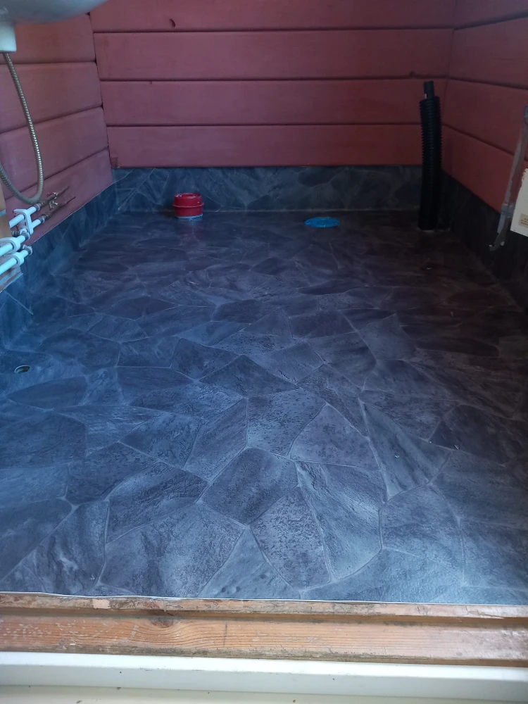 The image shows a bathroom floor with a dark blue, textured tile pattern. The tiles have an irregular, jagged appearance, creating a unique and visually interesting design.